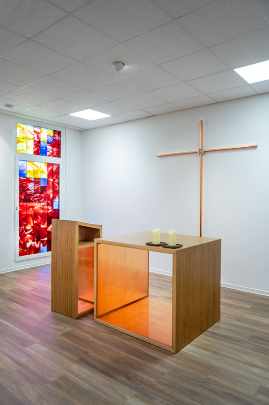 Lesepult, Kreuz, Altar mit Buntglasfenster im Hintergrund