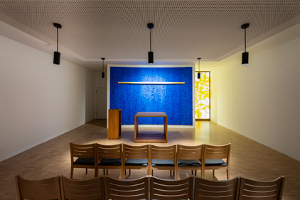 Ansicht der Kapelle mit Altar, blauer Rückwand und gelbem Glasfenster