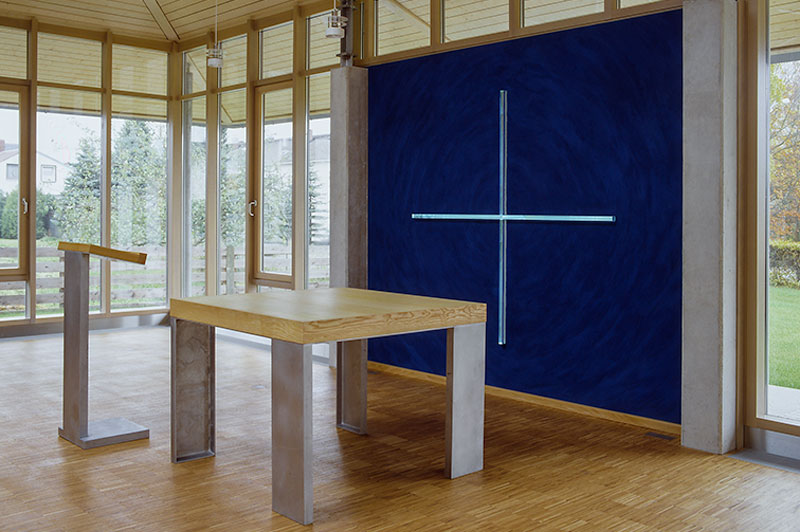 Altarraum, im Hintergrund Plexiglaskreuz in dunkelblauer Wand